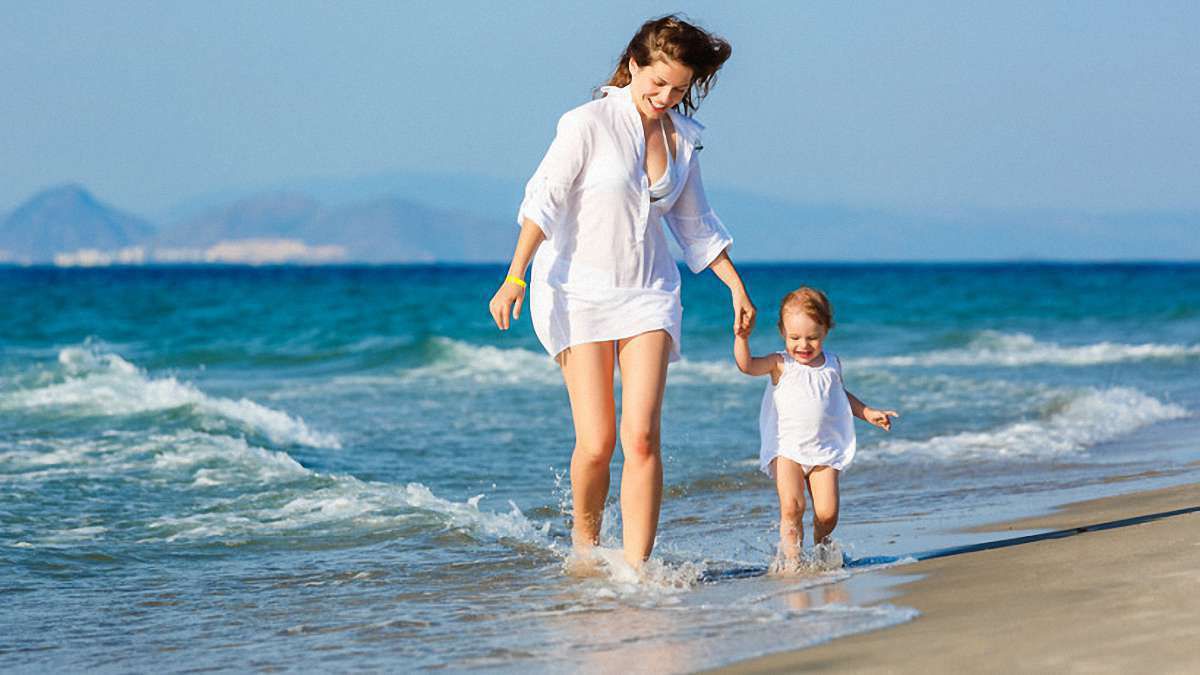 Женщина с ребенком на руках пляж