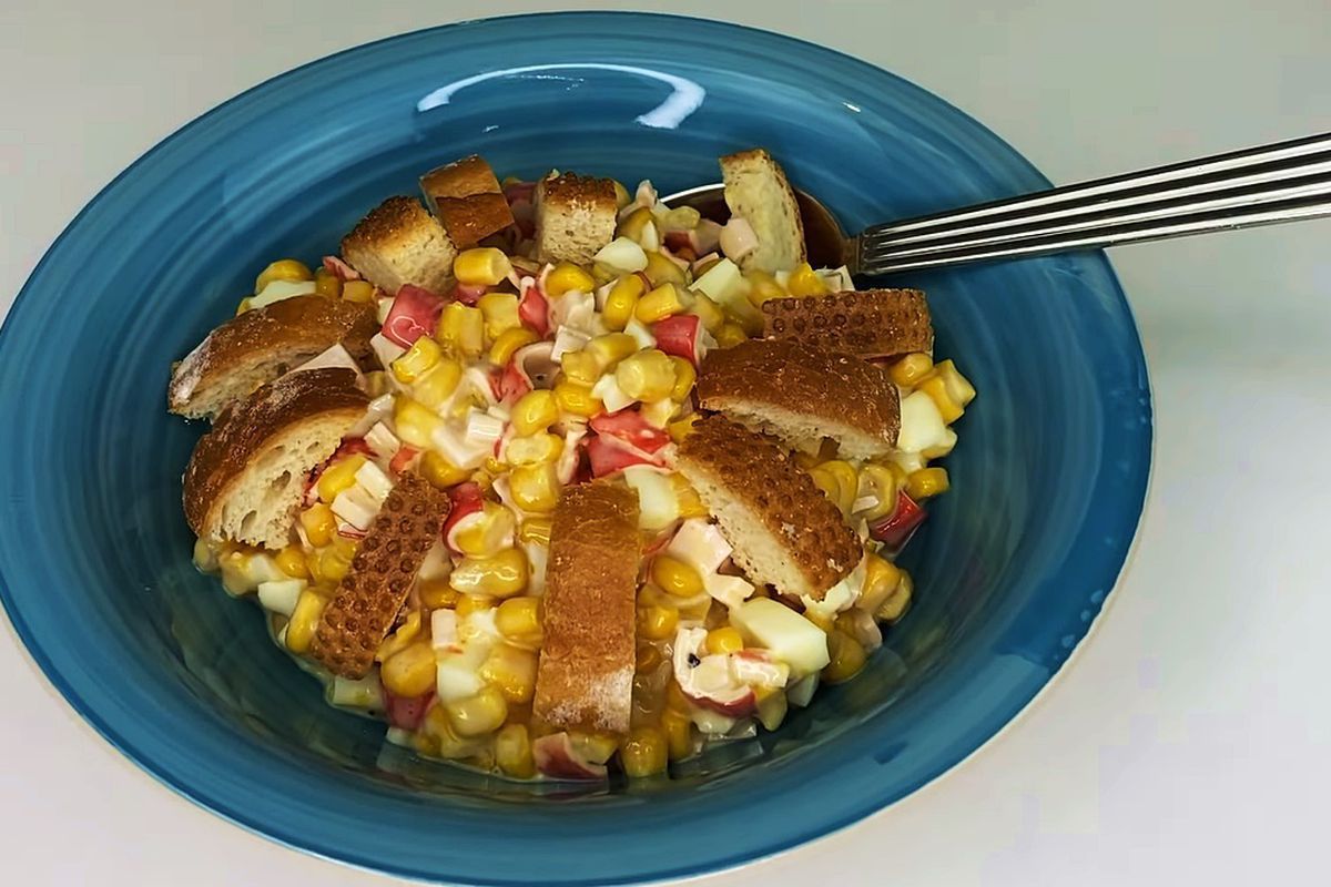 Святковий салат з крабовими паличками, кукурудзою і сухариками з сирною заправкою. Спробуйте улюблену закуску по-новому рецепту.