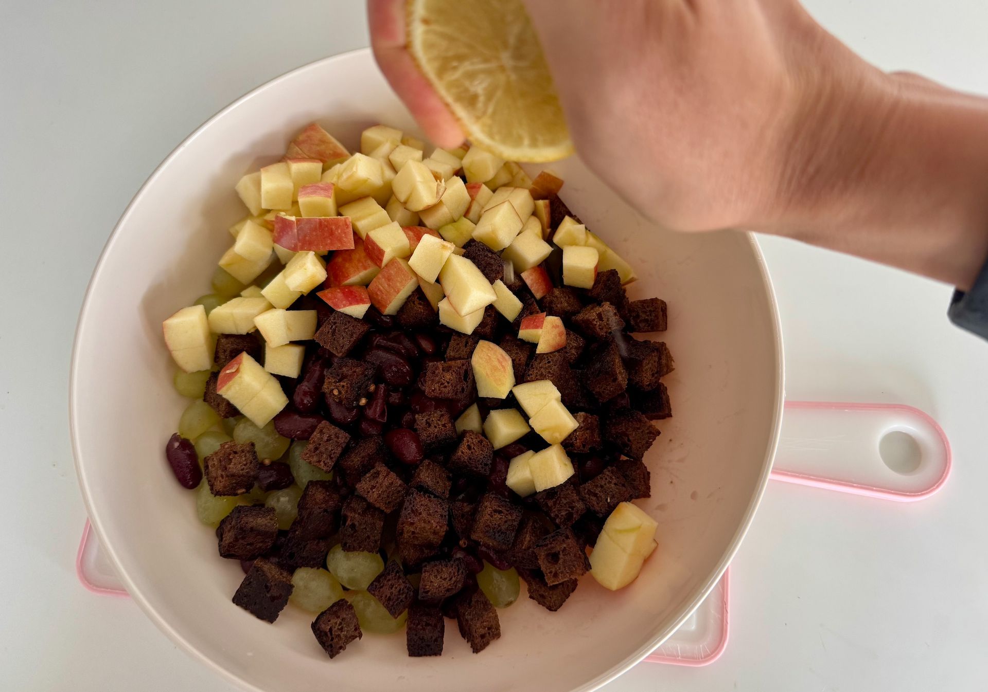 Процес приготування салату: нарізані яблука, виноград кишмиш та червона квасоля