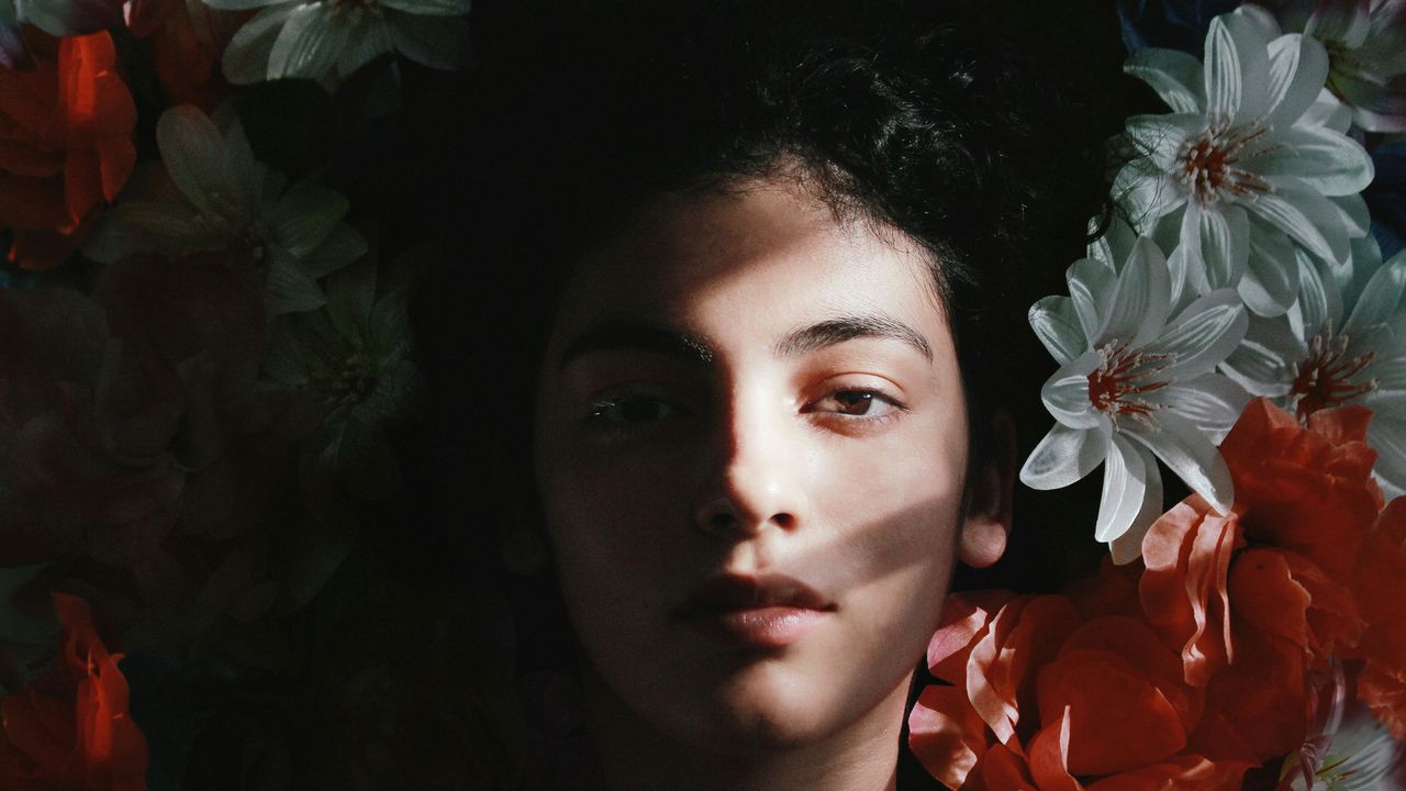 Сумна жінка серед квітів у тіні — ілюстрація до історії про зраду чоловікові та важливий життєвий урок.