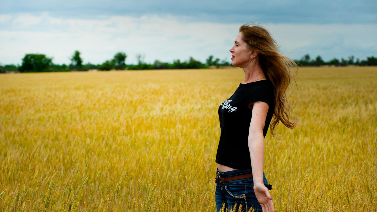 Натхненна жінка в золотистому полі пшениці, яка символізує перехід до яскравого життя та позитивних емоцій без жалю до себе.