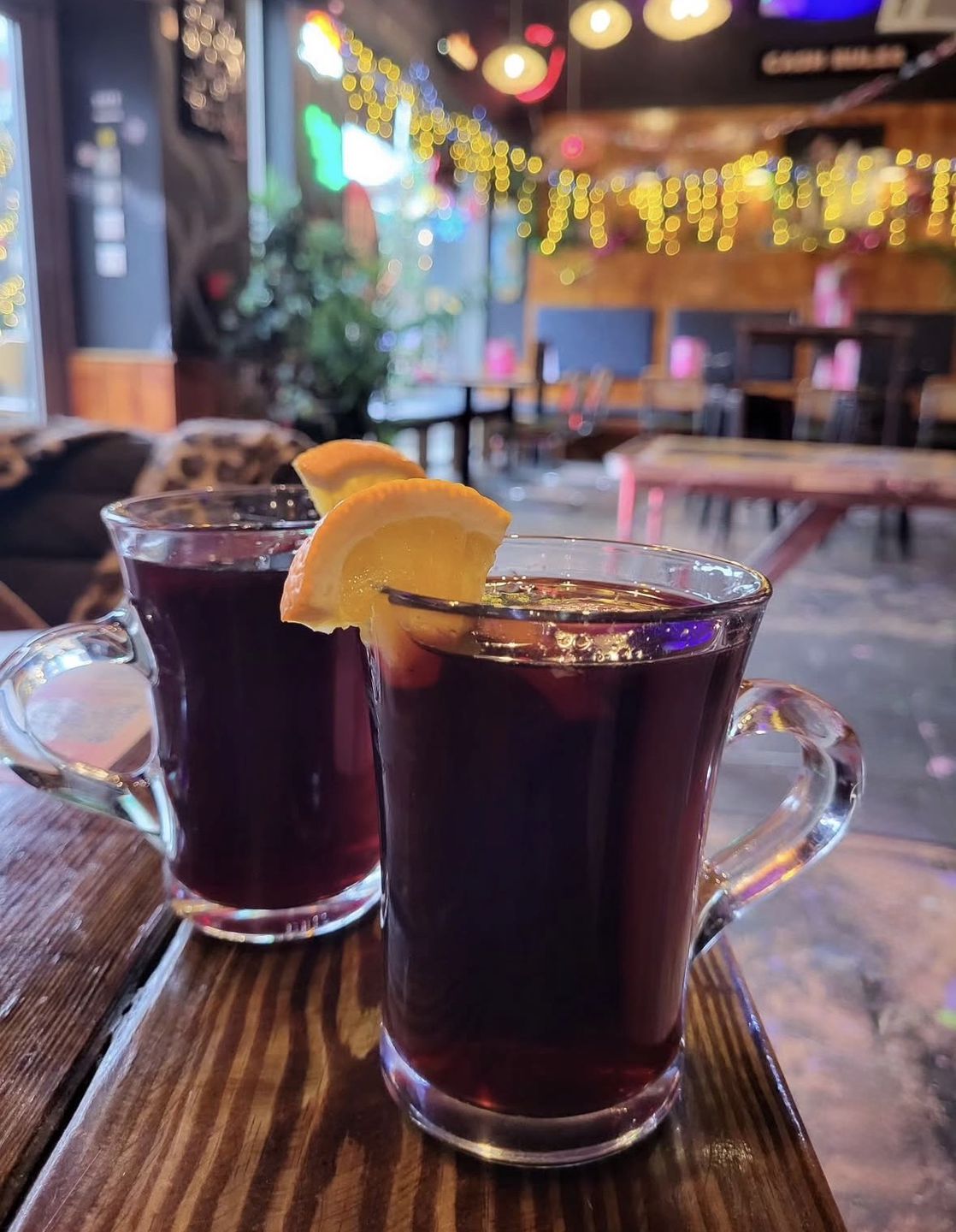 Дві чашки гарячого глінтвейну з апельсином на дерев'яному столі — популярний зігрівальний напій для зимового затишку