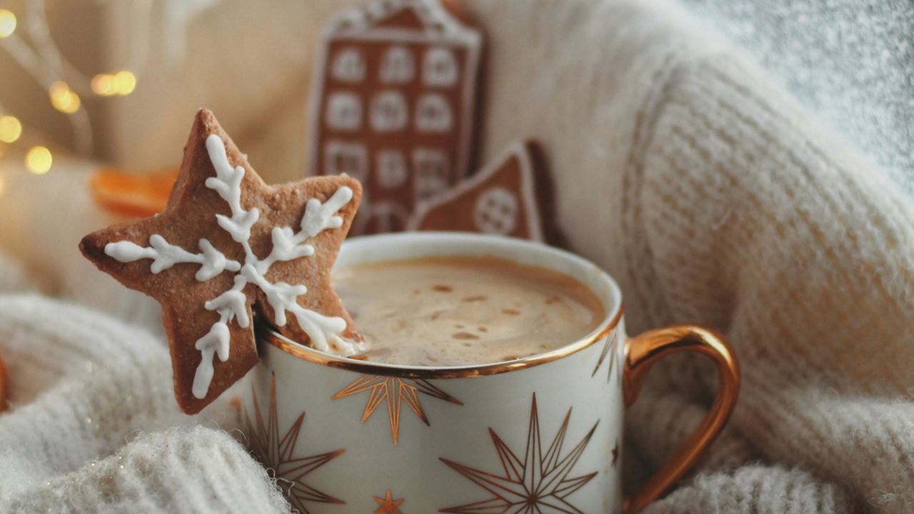 Зігрівальний напій в святковій чашці на фоні новорічного декору