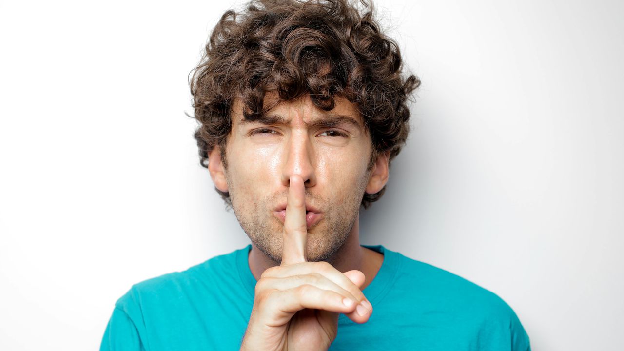 Чоловік тримає палець біля губ, символізуючи секрет того, яке чоловіче тіло насправді найбільше приваблює жінок.
