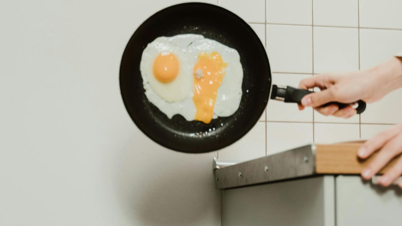 Смаження яєчні на антипригарній сковорідці, до якої почала прилипати їжа через знос покриття.