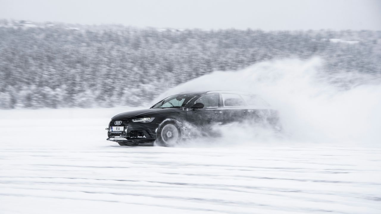 Чорний автомобіль буксує на снігу — як виїхати на крижаний підйом та що робити під час пробуксовки колес.