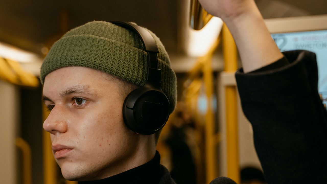 Хлопець у навушниках слухає музику в транспорті для зняття стресу та заспокоєння нервової системи.
