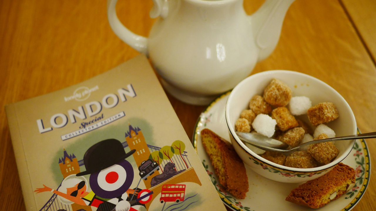 Коричневий та білий цукор у кубиках у мисці поруч із чайником – порівняння користі тростинного та рафінованого цукру.