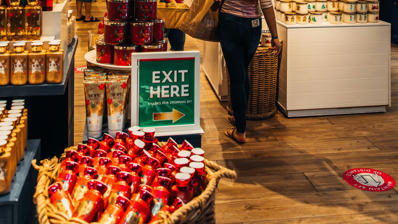 Жінка в магазині біля покажчика EXIT HERE, що ілюструє тему дотримання правил та культури поведінки покупців щодо персоналу.