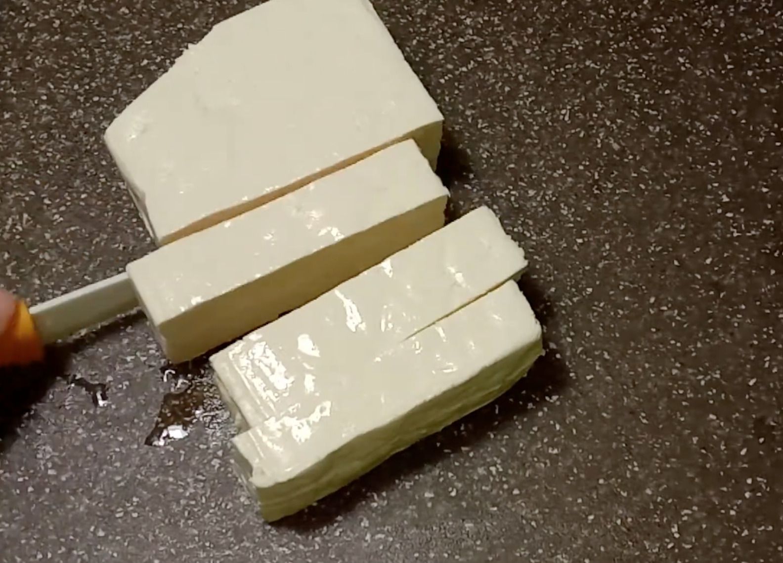 Нарізаний скибочками білий рослинний сир тофу на кухонній поверхні