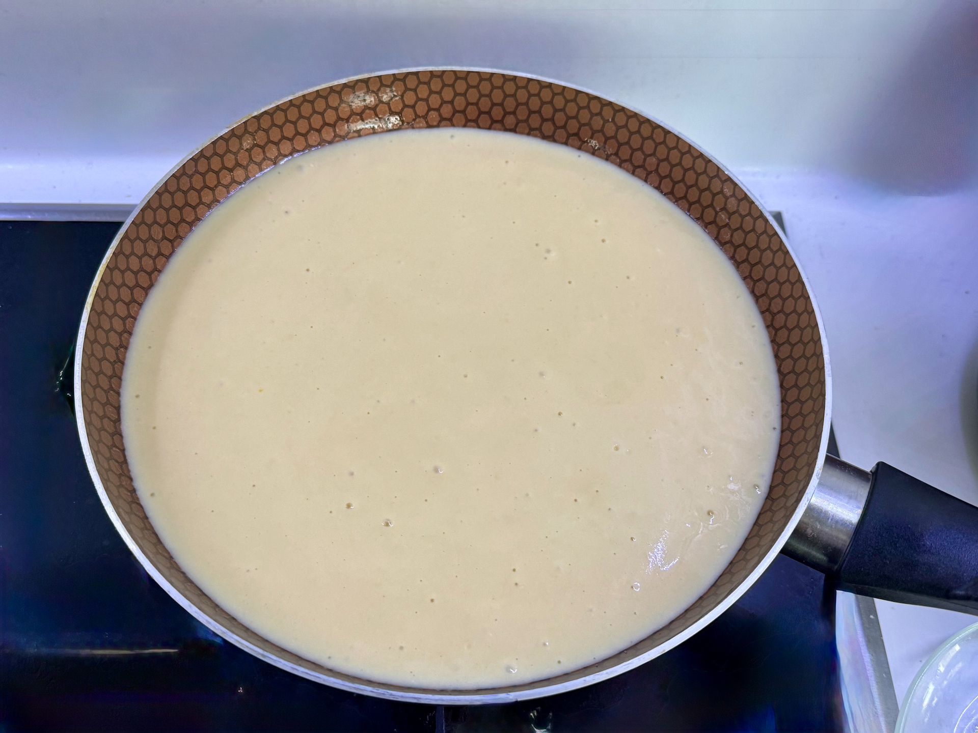 Процес заливання яблучного шару тістом для пирога на пательні