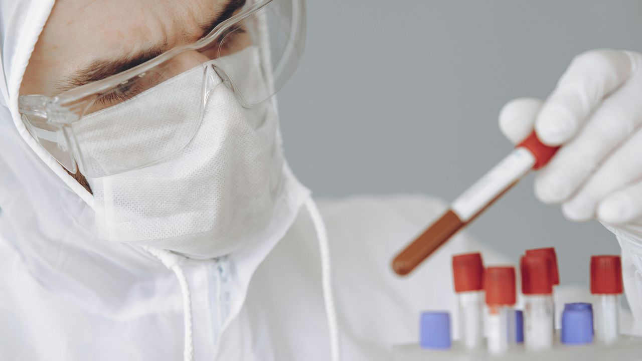 Науковець у захисному спорядженні проводить генетичне дослідження крові, що символізує вплив генів на здоров'я та життя людини.